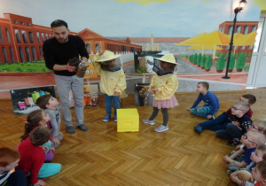 Dwoje dzieci ubranych w strój pszczelarski, pszczelarz, dzieci w kole